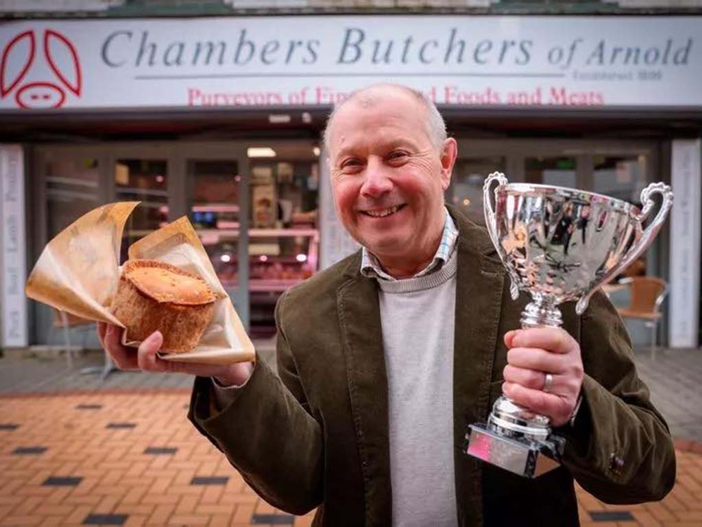 Philip Chambers in front of the Front Street shop fascia with a British Pie Awards trophy and a pork pie