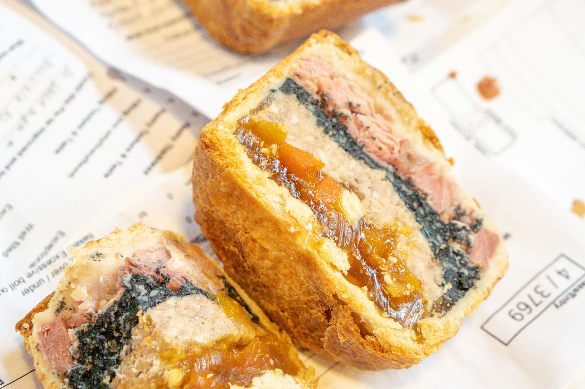 Pork pie cross-section on newsprint showing pastry, meat and jelly layers